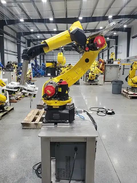 Yellow FANUC industrial robot arm mounted on a stand